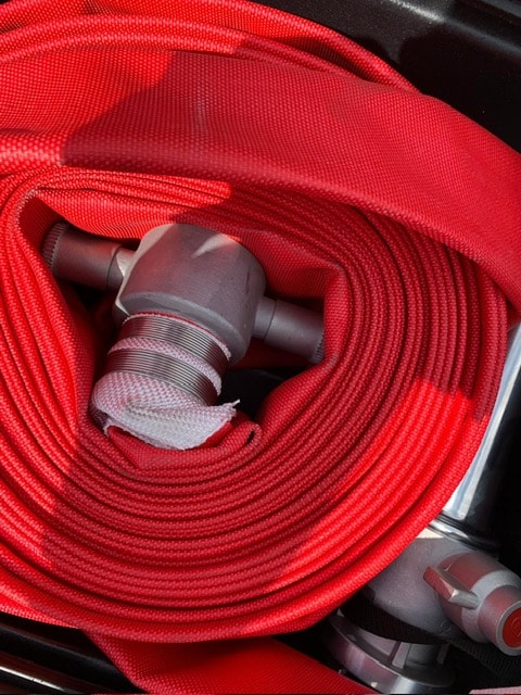 FIRE HOSE ASSEM Red fire hose coiled with metal connectors visible.